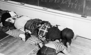 1950s children practicing duck and cover for bomb warnings